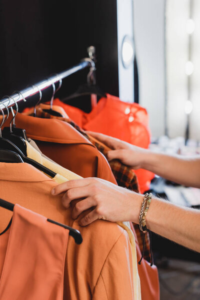 cropped view of stylist choosing clothes for photo shoot on backstage 