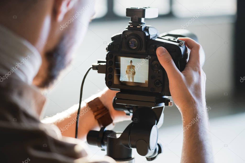 cropped view of photographer taking photo with digital camera on backstage