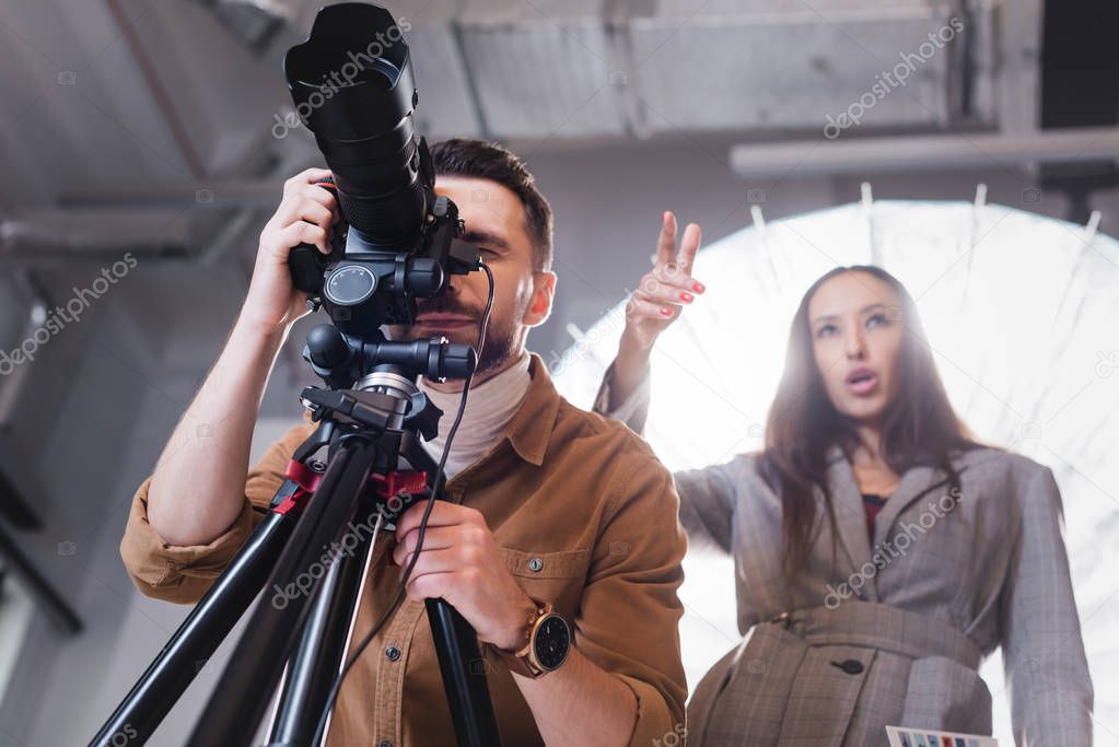 low angle view of photographer taking photo and producer pointing with finger on backstage 