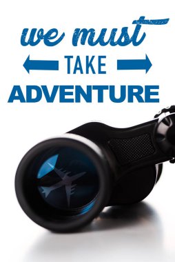 close up of black binoculars near we must take adventure letters on white  clipart