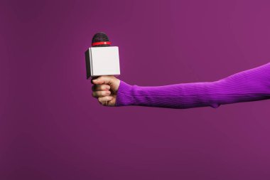 cropped view of reporter holding microphone on purple background clipart