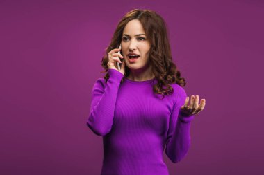 Şaşırmış bir kadın mor arka planda akıllı telefondan konuşuyor.
