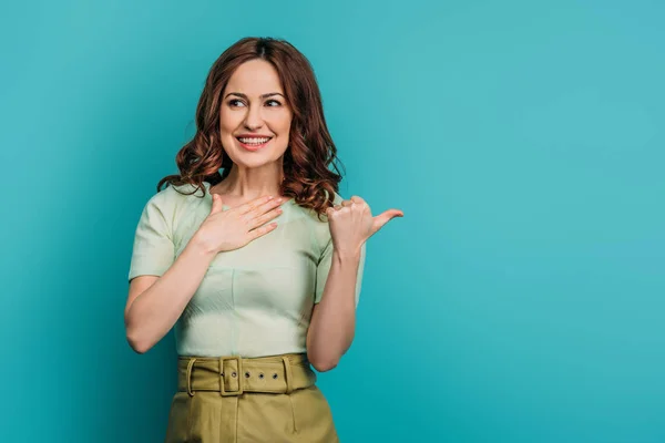 Surprised Smiling Woman Pointing Thumb Holding Hand Chest Blue Background — Stock Photo, Image
