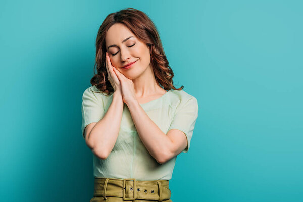 sleepy woman standing with closed eyes on blue background