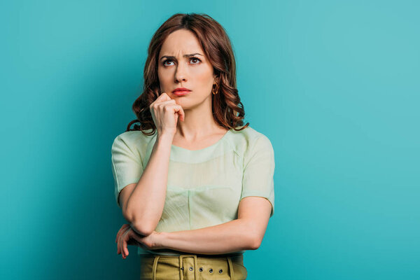 thoughtful woman looking up while standing on blue background