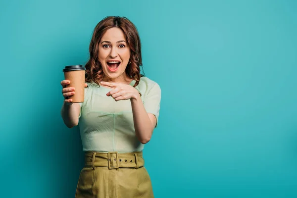 Cheerful Girl Pointing Finger Paper Cup Blue Background — Stock Photo, Image