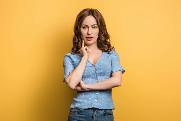 Ragazza Pensierosa Che Tocca Viso Mentre Guarda Fotocamera Sfondo Giallo — Foto Stock