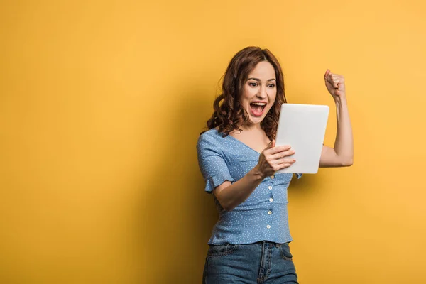 Vzrušená Žena Ukazuje Vítězný Gesto Zatímco Drží Digitální Tablet Žlutém — Stock fotografie
