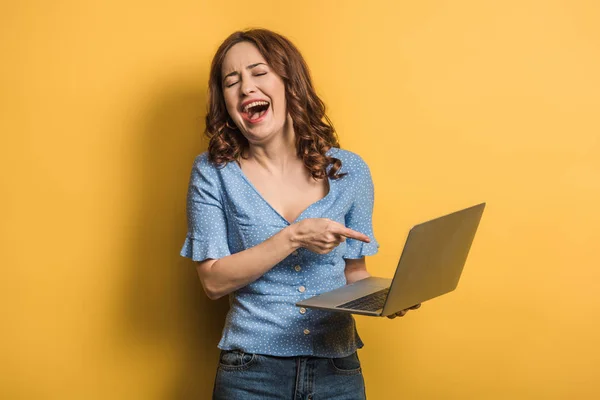 Menina Alegre Rindo Apontar Com Dedo Para Laptop Fundo Amarelo — Fotografia de Stock