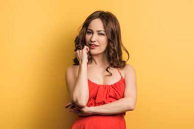 Hayalperest genç bir kadın el ele tutuşuyor ve sarı arka plandaki kameraya bakıyor.