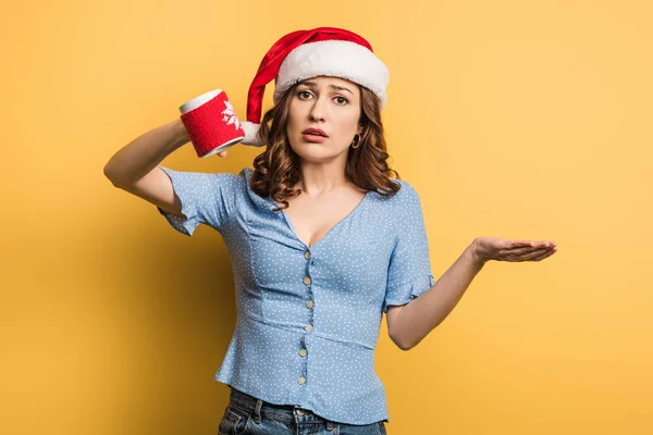 Chica Molesta Sombrero Santa Sosteniendo Taza Vacía Sobre Fondo Amarillo — Foto de Stock