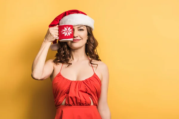 Cheerful Girl Santa Hat Covering Eye Cup Yellow Background — Stock Photo, Image