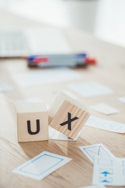 Selective focus of cubes with ux letters and website app layouts on wooden table clipart
