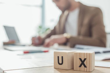 Selective focus of wooden cubes with ux letters and creative designer working at table clipart