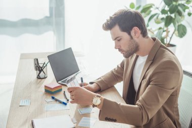 Mobil web sitesi için masadaki kablo çizimleriyle çalışan yakışıklı bir ux tasarımcısının yan görünümü