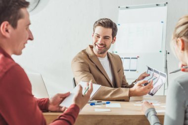 Tasarımcı stüdyosunda mobil uygulama arayüzü geliştiren gülümseyen tasarımcıların seçici odağı