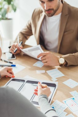 Mobil web sitesi için masadaki çizimleri planlayan yaratıcı tasarımcıların seçici odak noktası