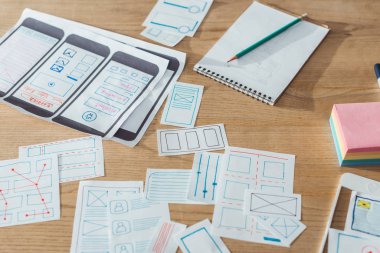 Selective focus of mobile website sketches and layouts on wooden table clipart