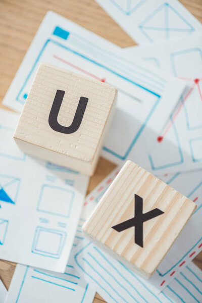 Top view of letter ux on wooden cubes with website template layouts on table