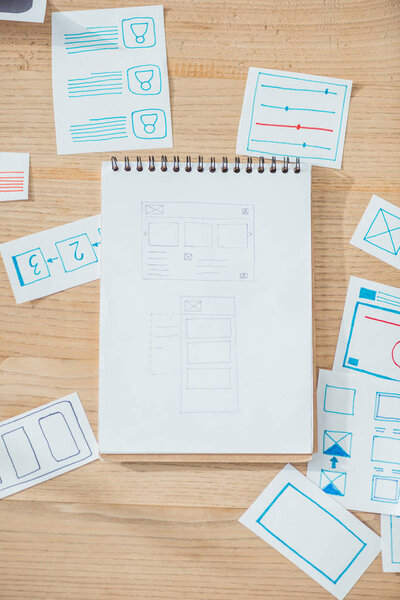 Top view of ux website wireframe sketches and planning applications on wooden table