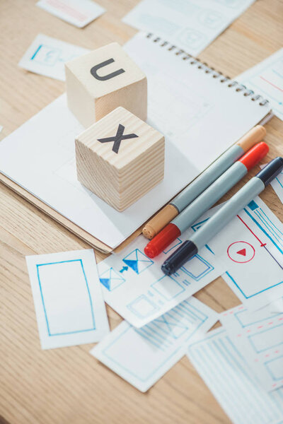 Selective focus of cubes with ux letters and website app layouts on wooden table