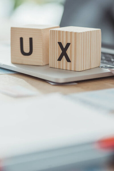 Selective focus of wooden cubes with ux letters on laptop on table
