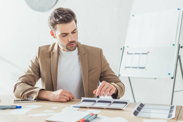 Креативный дизайнер планирует проект мобильных приложений с макетами в офисе
