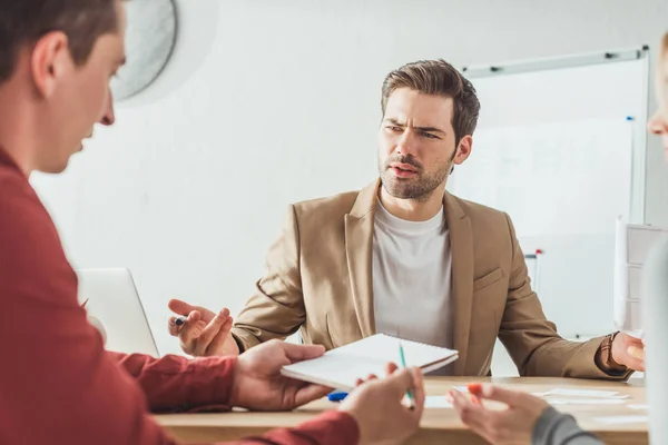 Enfoque Selectivo Del Diseñador Confuso Mirando Colega Con Cuaderno Mesa — Foto de Stock