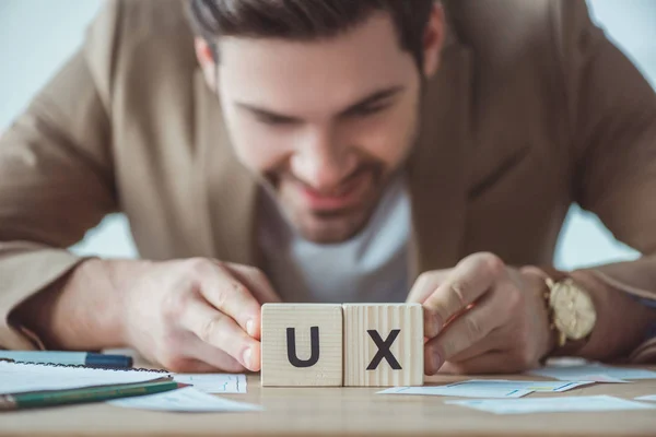 Foco Seletivo Sorrir Designer Criativo Segurando Cubos Com Letras Mesa — Fotografia de Stock