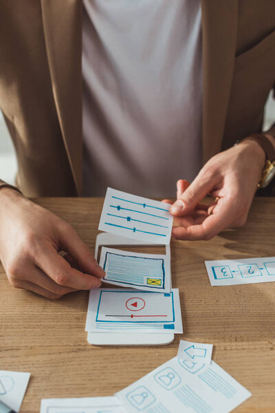 Cropped view of ux designer working with prototype of mobile app at table