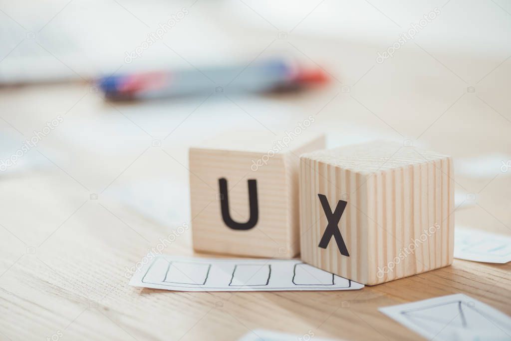 Selective focus of wooden cubes with ux letters and web sketches on table