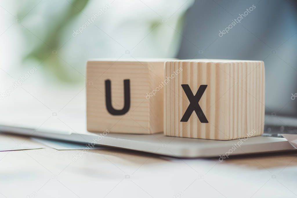 Selective focus of wooden cubes with ux letters on laptop on table