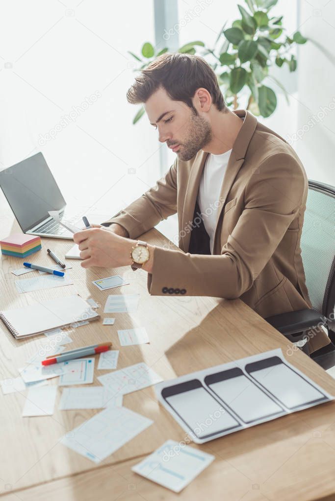 Side view of creative designer making sketches of app interface at office table