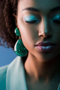 Çekici Afro-Amerikan kadın, gözleri kapalı ve makyajlı, mavi üzerine izole edilmiş.