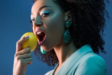 Çekici Afrikalı Amerikalı kadın diş telleri ile limon yiyor.