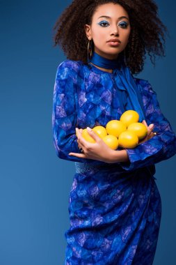 Çekici Afrikalı Amerikalı kadın limon tutuyor mavi üzerinde. 