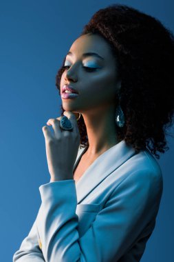 Ceketli Afro-Amerikan kadın, tek başına mavi tarafa bakıyor. 