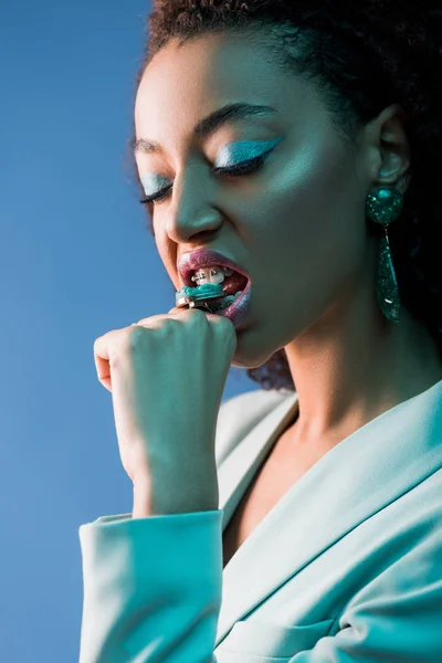 Κομψή Αφροαμερικανή Γυναίκα Δαχτυλίδι Δάγκωμα Μακιγιάζ Απομονωμένο Στο Μπλε — Φωτογραφία Αρχείου