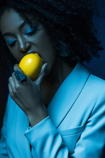 Atractiva Mujer Afroamericana Con Maquillaje Comer Limón Aislado Azul —  Fotos de Stock