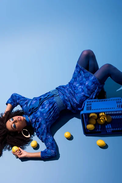 African American Woman Lying Shopping Basket Lemons Blue Background — Stock Photo, Image