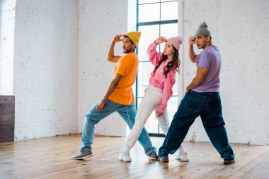 Dans stüdyosunda break dans yaparken şapkalara dokunan çok kültürlü dansçılar. 