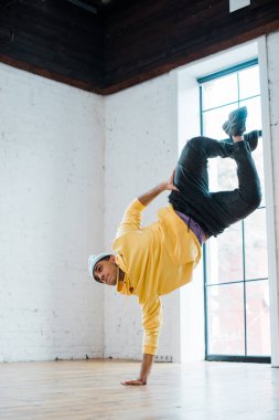 trendy man in hat breakdancing in dance studio  clipart