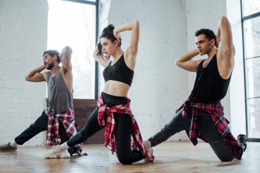 Yakışıklı, çok kültürlü erkekler ve çekici bir kadın caz funk dansı yaparken saçlarına dokunuyor. 