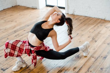 young flexible woman posing while dancing jazz funk in dance studio  clipart
