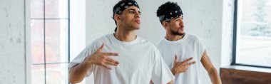 Kafasında bantlarla hip-hop dansı yapan çok kültürlü dansçıların panoramik çekimi.