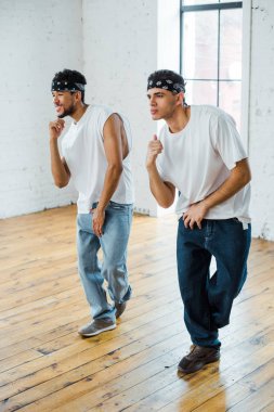 Saç bantlı, hip-hop dansı yapan yakışıklı çok kültürlü dansçılar.