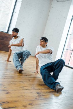 Saç bantlı yakışıklı çok kültürlü adamlar hip-hop dansı yapıyor.