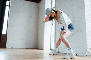 Hip-hop dansı yaparken şapkaya dokunan çekici kız. 