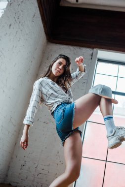 low angle view of pretty dancer with cap dancing hip-hop in dance studio 