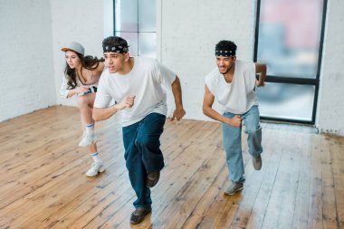 selective focus of handsome multicultural dancers in headbands dancing with girl